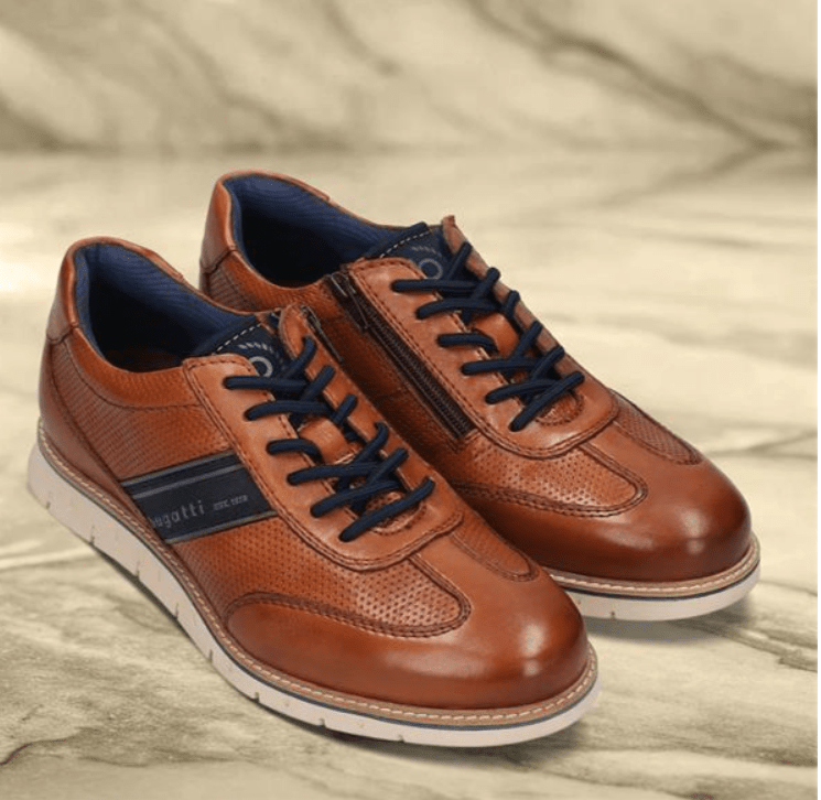 Brown coloured shoes on a beige background featuring two navy stripes, navy laces and a navy zip
